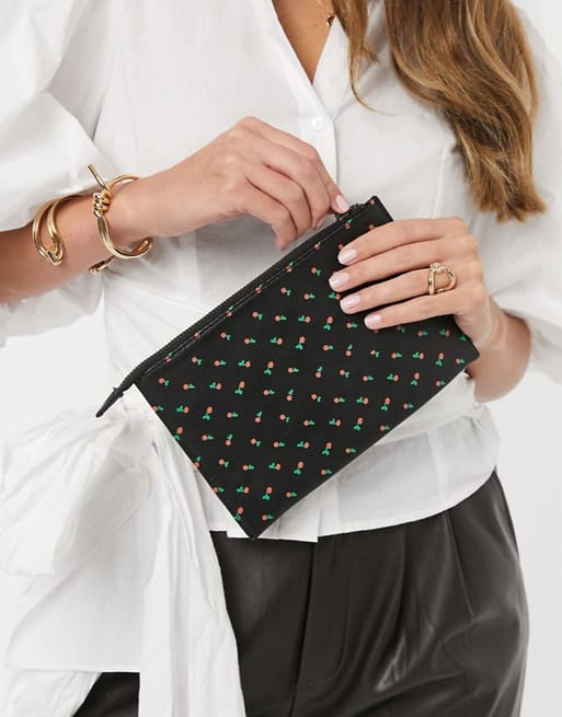 A woman is holding a black cherries clutch.