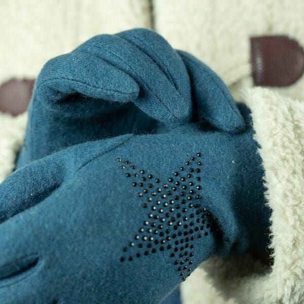 A woman adorned in teal wool gloves with star embellishments.