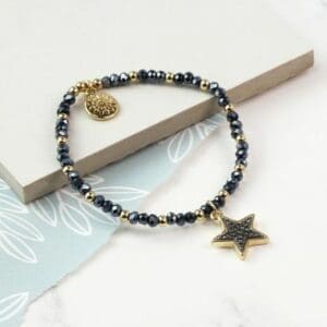 A stylish stacking bracelet featuring a gold star charm on a black and gold design.