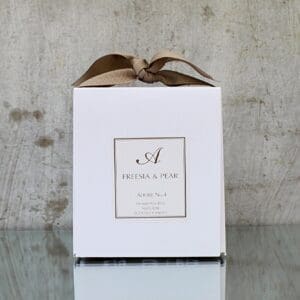 A white Soy Wax Candle - Freesia & Pear adorned with a bow.