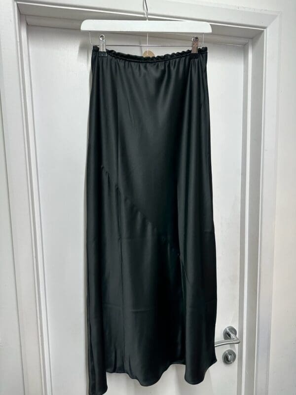 A black skirt hanging on a door.