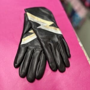 A pair of black and gold gloves on a pink table.