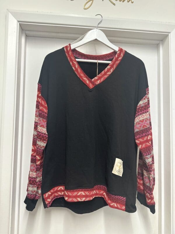 A black and red sweater hanging on a door.