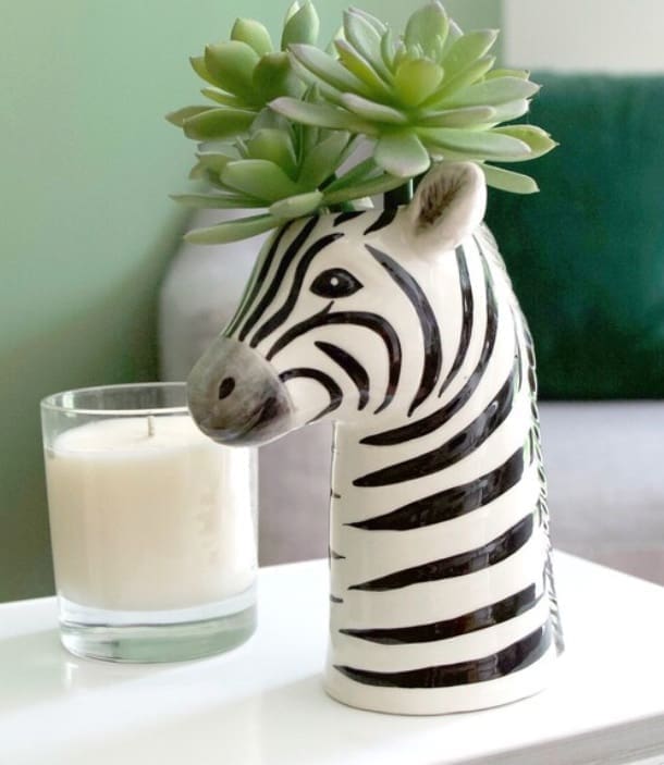 A zebra shaped vase with succulents in it.