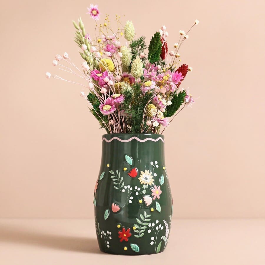 A green vase with flowers on it.