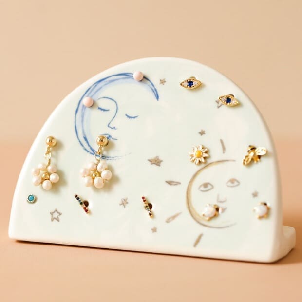 A ceramic earring holder with a moon and stars on it.