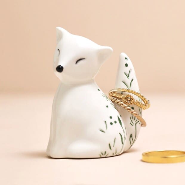 A ceramic fox ring holder with rings on it.