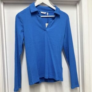A blue polo shirt hanging on a door.