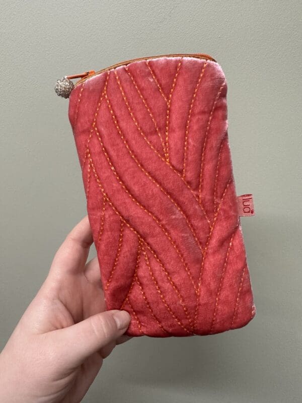 A person holding up a red zippered pouch.