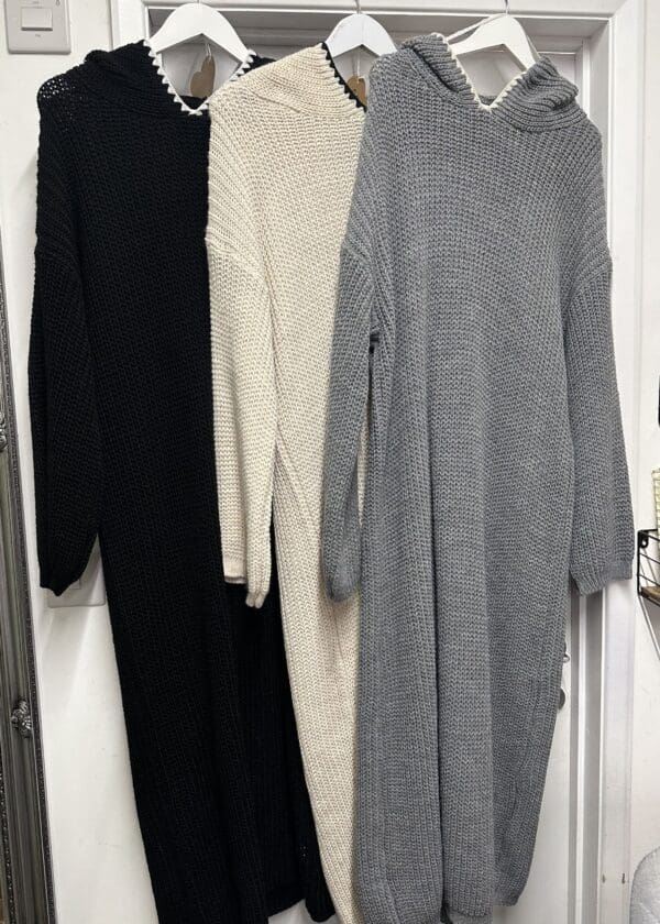 Three sweaters hanging on a hanger in a room.