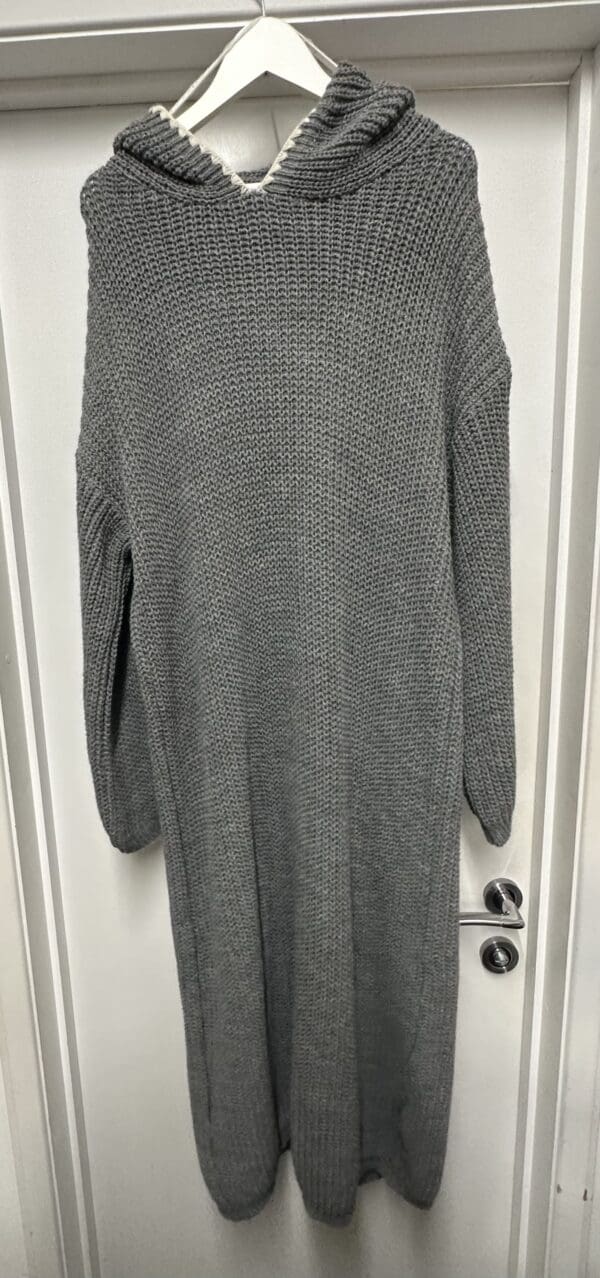 A grey sweater hanging on a door.