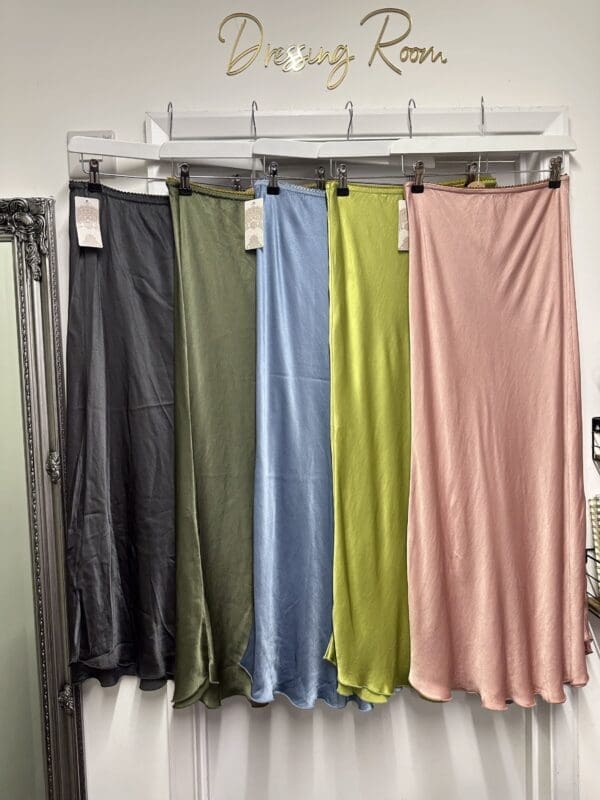 A group of Satin Skirts in Lime hanging on a rack.